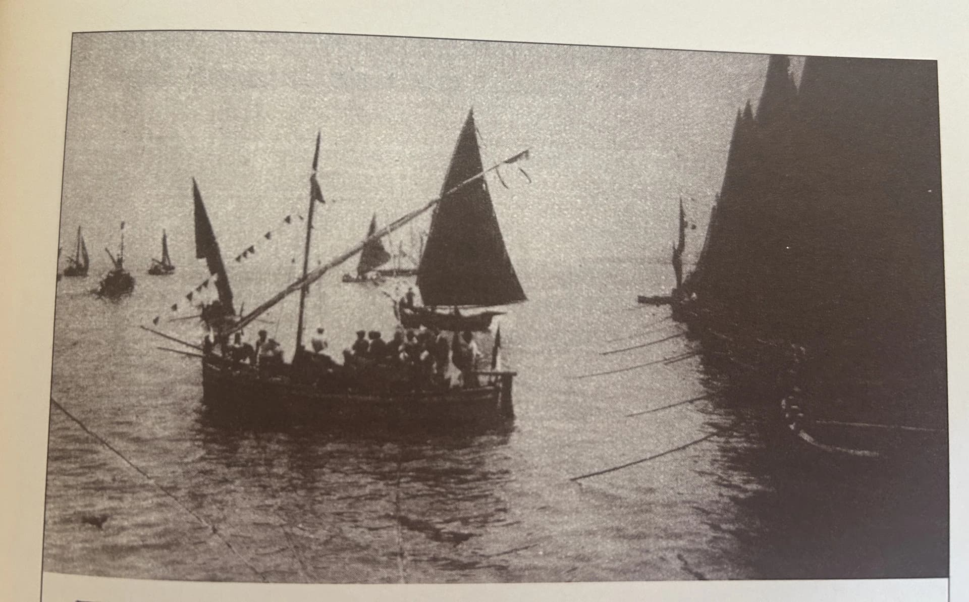 Fotografia d’epoca di barche a vela cariche di persone, riprodotta nella raccolta di riferimento